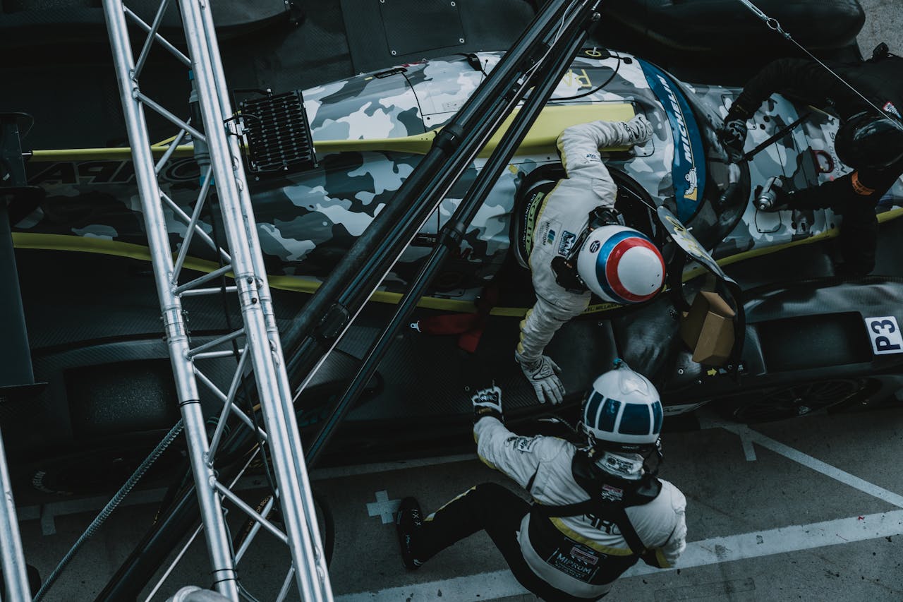 A dynamic overhead view of a pit stop during a formula racing event, showcasing teamwork and precision.